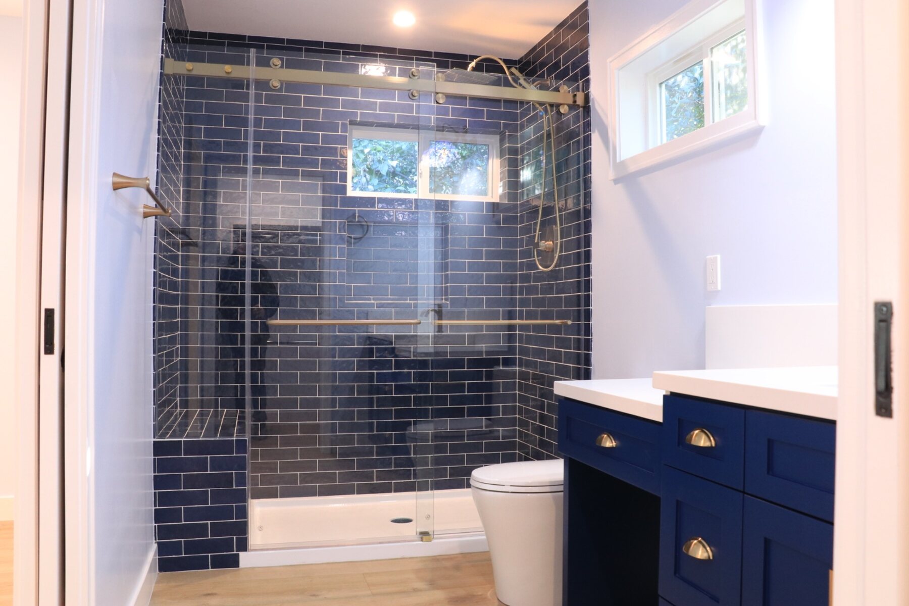 Completed bathroom with deep blue tile and custom navy vanity