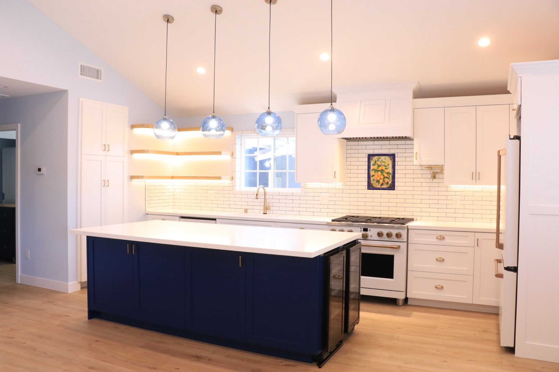 Completed custom kitchen remodel with navy island, white cabinetry, and integrated lighting